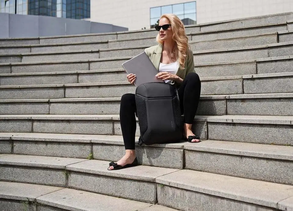 Frau mit Laptop und Business-Rucksack sitzend auf der Treppe