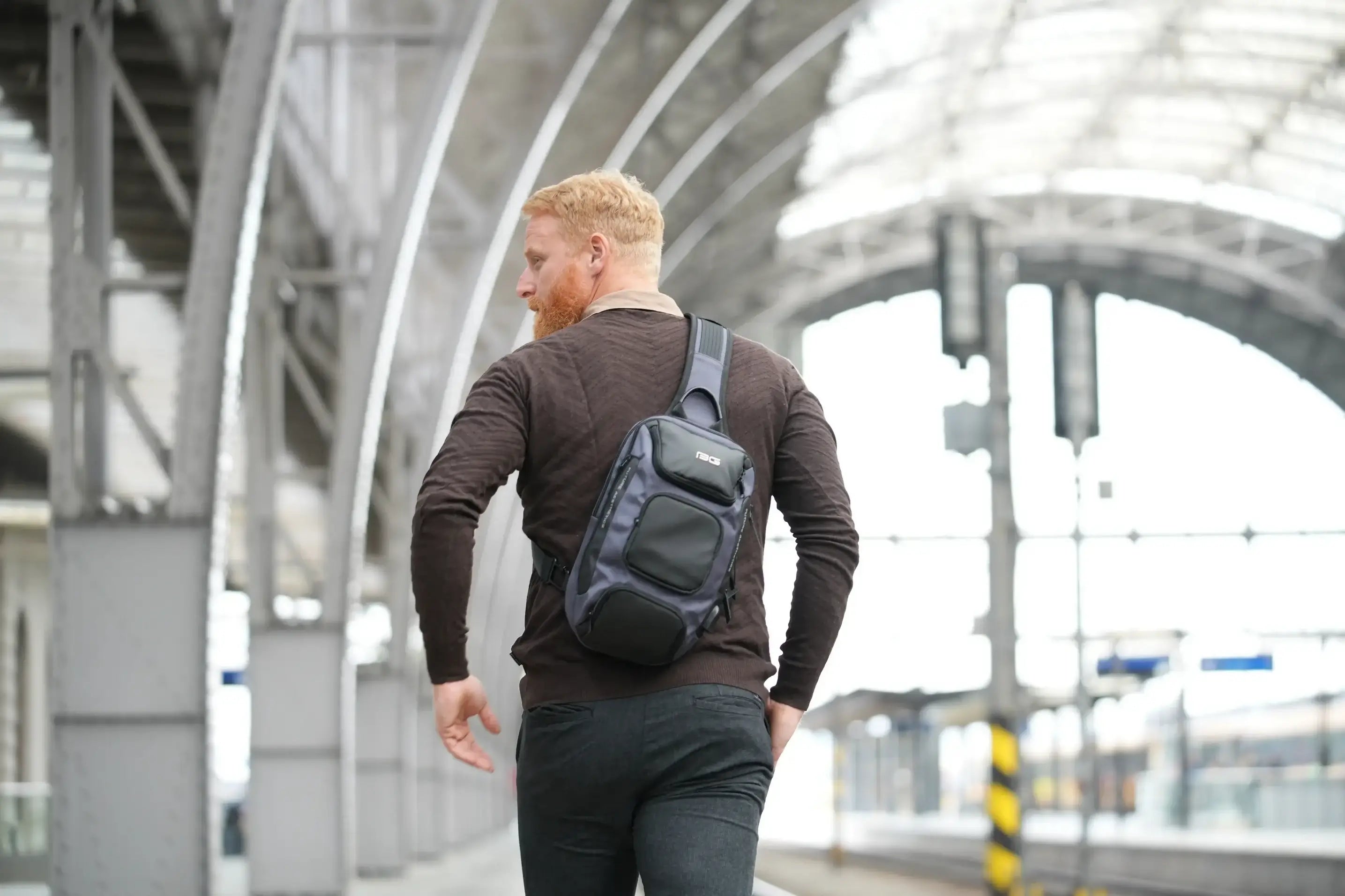 Man mit Cross-Bag am Rücken an einem Bahnhof